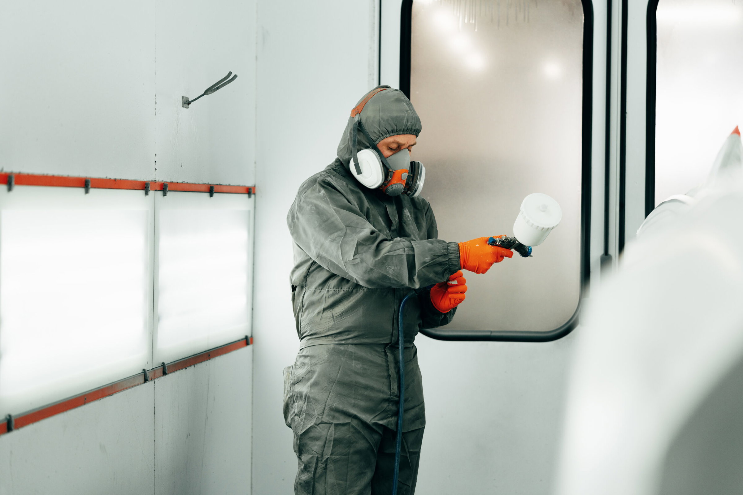 Auto painter painting a car with vaporizer gun inside a paint booth close up